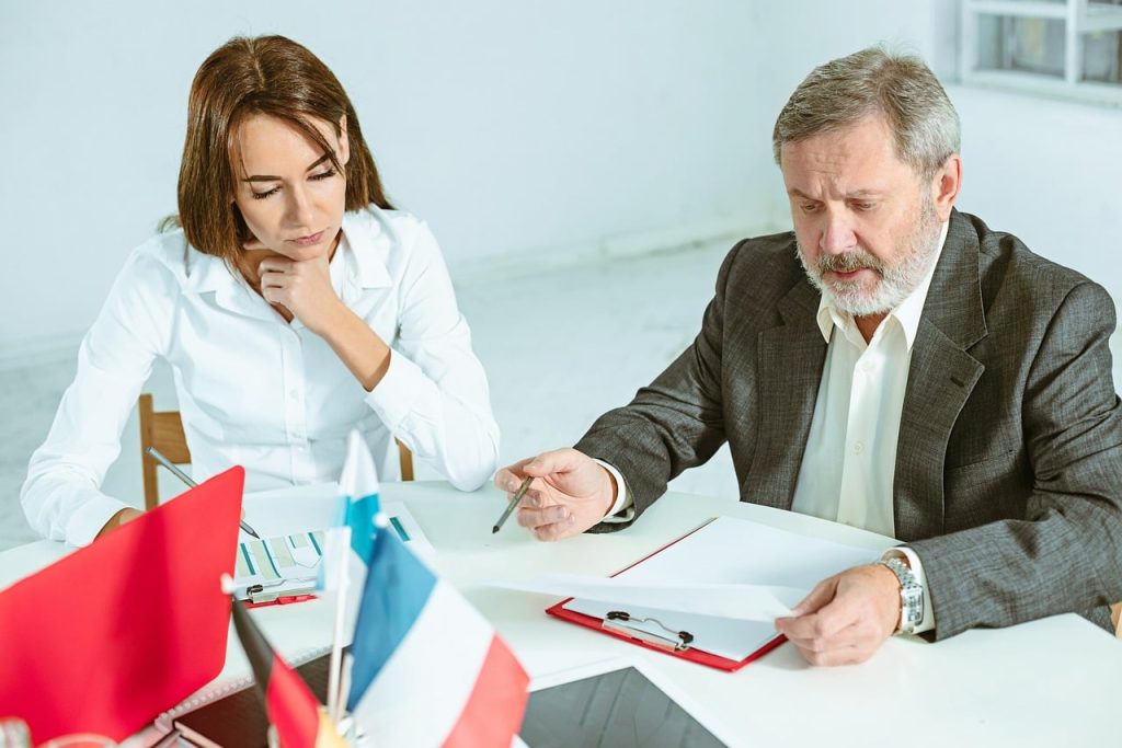 Klientka konsultuje się z prawnikiem przy biurku, przeglądając dokumenty przed podpisaniem umowy