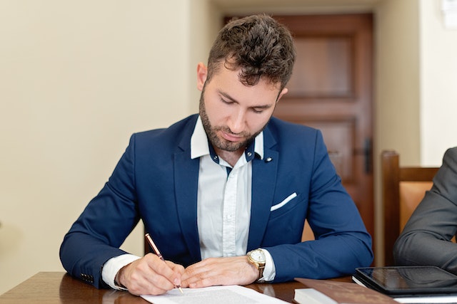 mężczyzna podpisujący dokumenty